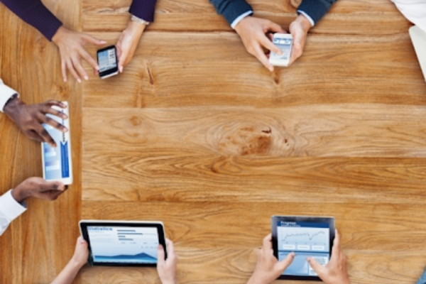 Diversas pessoas utilizando aparelhos móveis sobre uma mesa